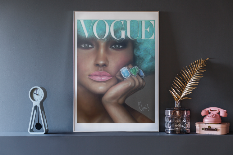 Vogue pastel drawing of a woman with turquise hair, pink lips and blue rings on her fingers in a frame standing on a dark grey shelf next to a gold feather and a pink phone