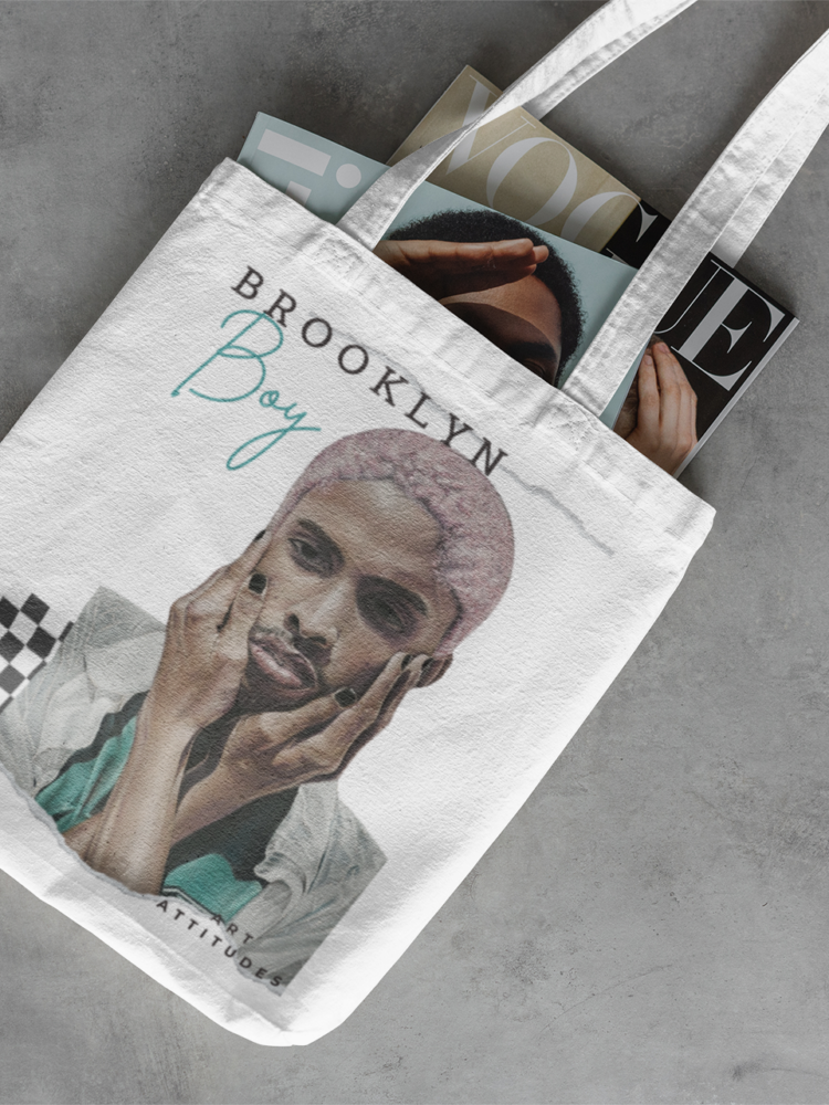 white tote bag with a boy holding his hands on his face field with magazines on a concrete floor