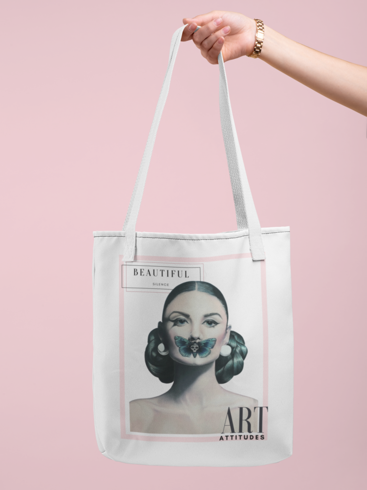 Hand holding a white tote bag with a motive of a woman with a butterfly over her mouth