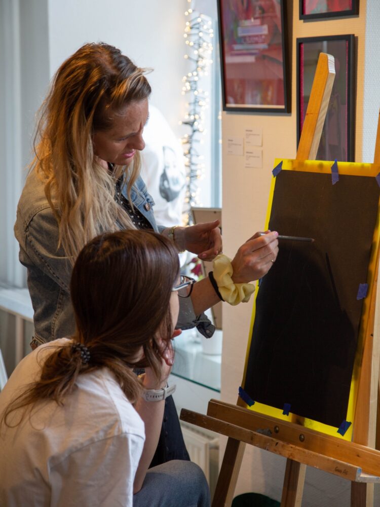 Christine Petersen guiding a student that's drawing a black and white drawing